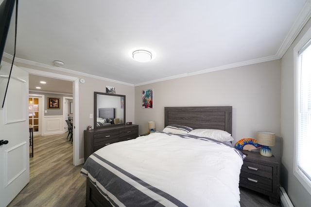 bedroom with multiple windows, a baseboard radiator, crown molding, and wood finished floors