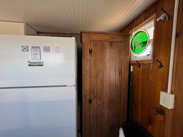 interior details featuring wooden walls and freestanding refrigerator