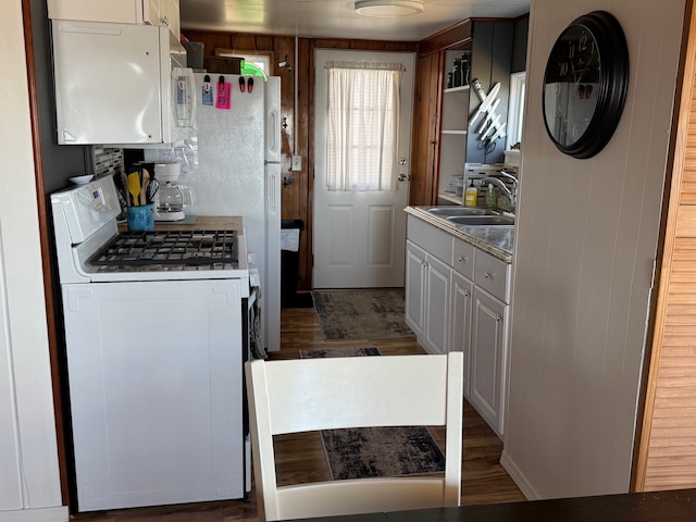 kitchen with white appliances, dark wood-style floors, and a sink