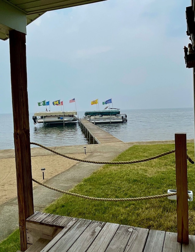 dock area with a lawn and a water view