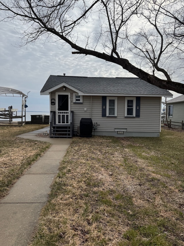 bungalow-style home with a front yard and roof with shingles