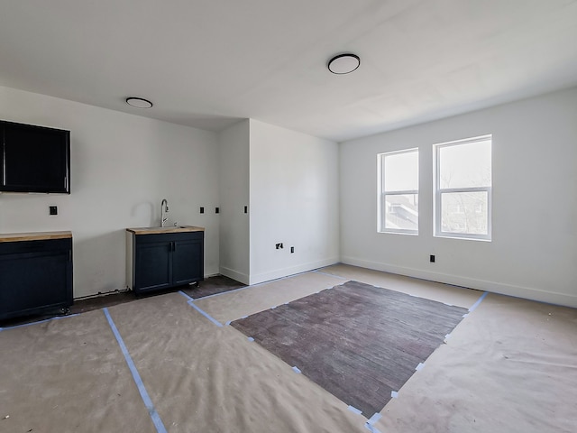 11765 Glenfield St, Detroit, MI 48213 - unfurnished living room featuring concrete floors, a sink, and baseboards