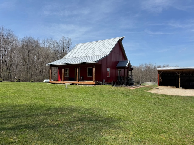 exterior space with a lawn, a detached carport, and metal roof
