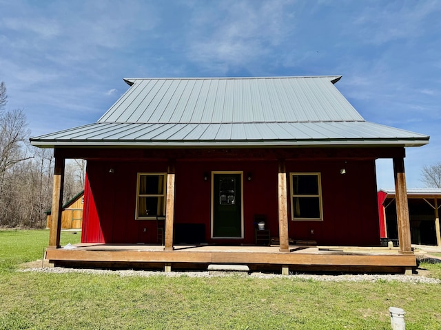 rear view of house with metal roof, a yard, covered porch, and a standing seam roof
