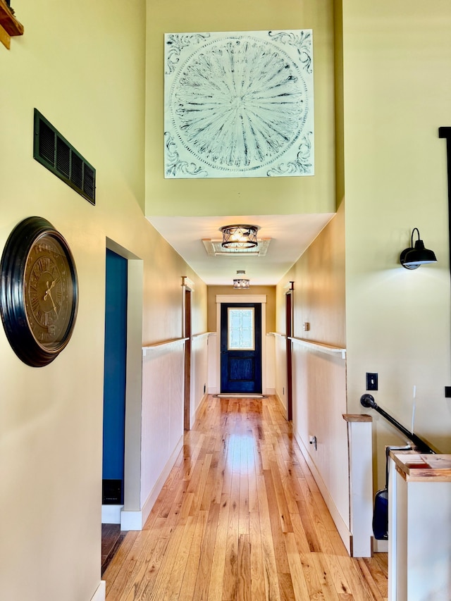 hall with baseboards, visible vents, and light wood-style floors