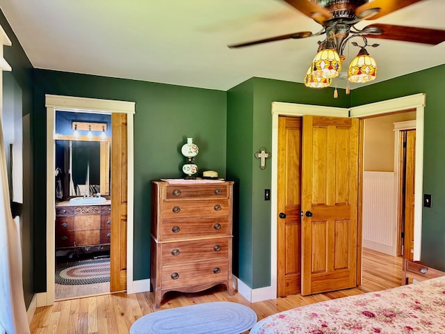 bedroom with a closet, baseboards, ceiling fan, and light wood-style floors