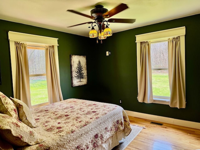 bedroom featuring baseboards, visible vents, ceiling fan, and hardwood / wood-style floors