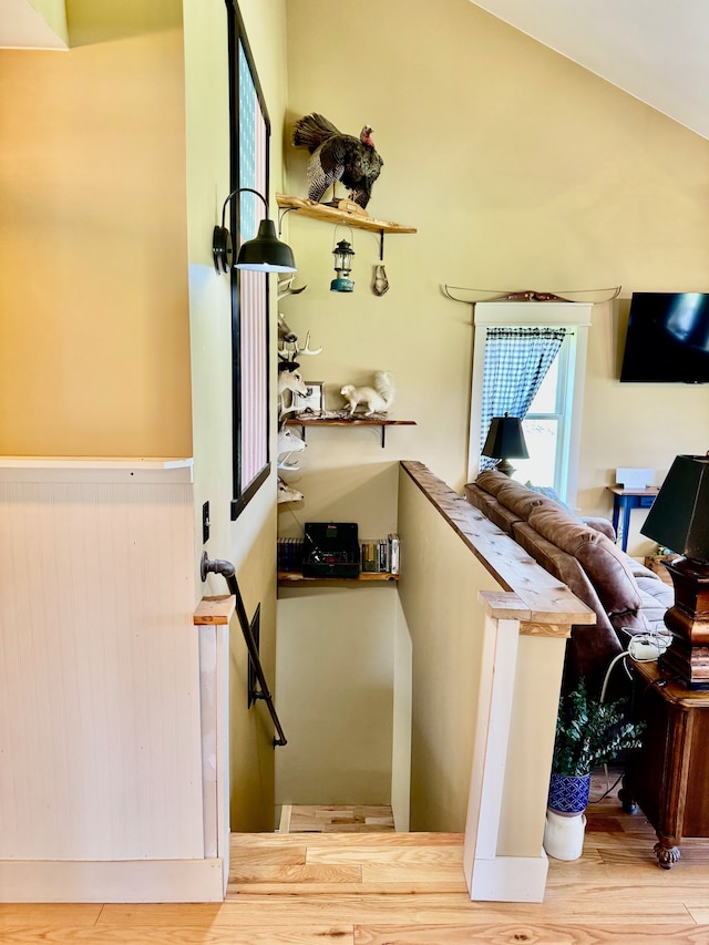 stairway with wainscoting and wood finished floors