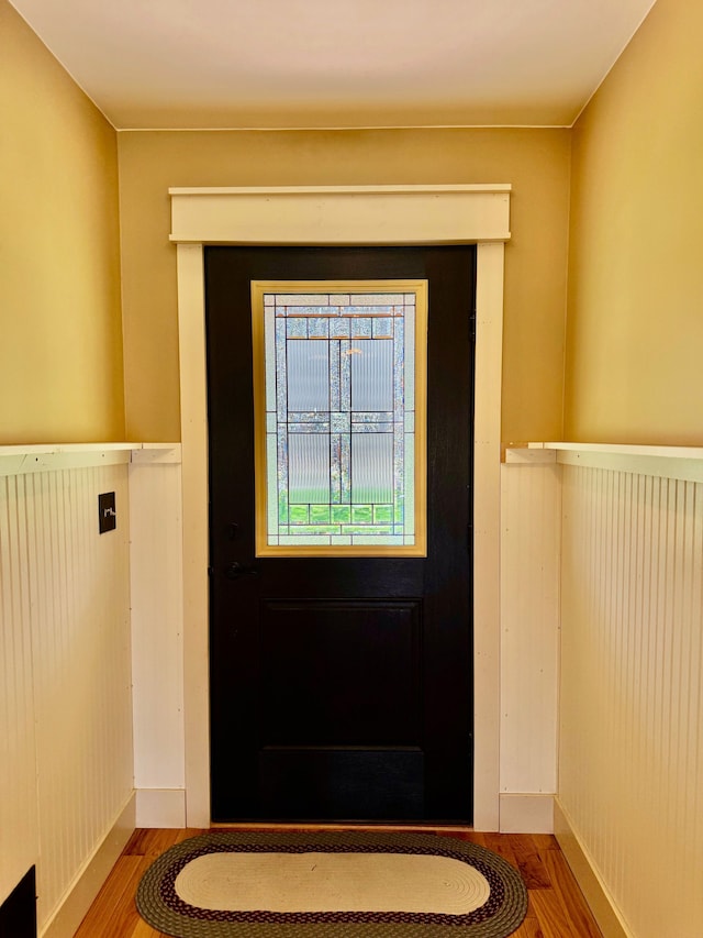 doorway to outside with a wainscoted wall and wood finished floors