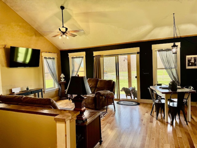 living area featuring baseboards, a ceiling fan, light wood-style flooring, and vaulted ceiling