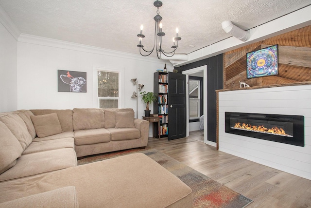 12934 Wilson Rd, Fruitport, MI 49415 - living area featuring crown molding, a textured ceiling, a glass covered fireplace, wood finished floors, and a notable chandelier