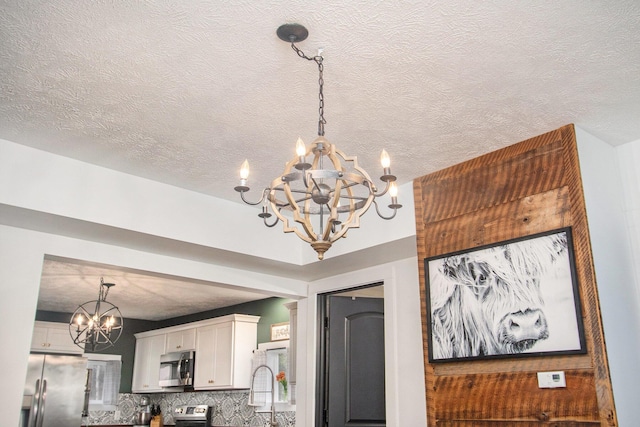 12934 Wilson Rd, Fruitport, MI 49415 - details with a chandelier, a textured ceiling, backsplash, stainless steel appliances, and a sink