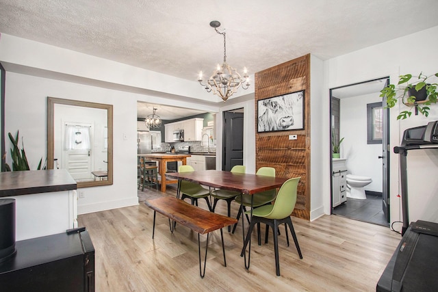 12934 Wilson Rd, Fruitport, MI 49415 - dining area with baseboards, an inviting chandelier, light wood-style floors, and a textured ceiling