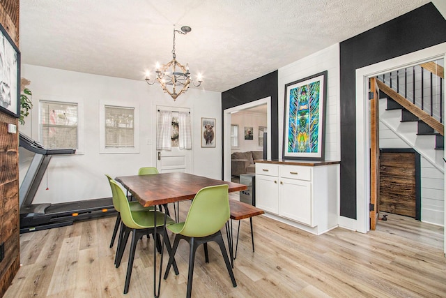 12934 Wilson Rd, Fruitport, MI 49415 - dining area featuring baseboards, an inviting chandelier, light wood-style floors, a textured ceiling, and stairs