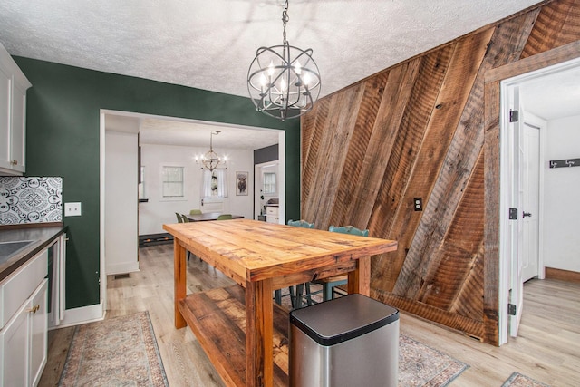 12934 Wilson Rd, Fruitport, MI 49415 - dining space featuring baseboards, a notable chandelier, light wood-style floors, and a textured ceiling