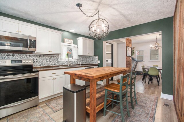 12934 Wilson Rd, Fruitport, MI 49415 - kitchen featuring wood counters, an inviting chandelier, visible vents, and stainless steel appliances
