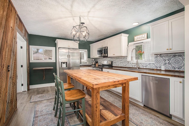 12934 Wilson Rd, Fruitport, MI 49415 - kitchen with an inviting chandelier, light wood-style flooring, appliances with stainless steel finishes, a sink, and decorative backsplash