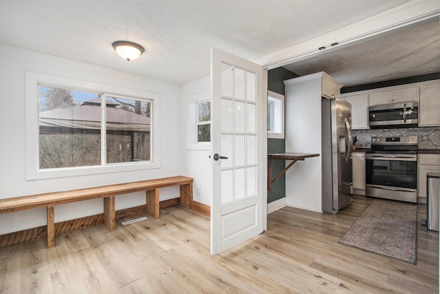 12934 Wilson Rd, Fruitport, MI 49415 - kitchen with stainless steel appliances, tasteful backsplash, light wood finished floors, and a textured ceiling