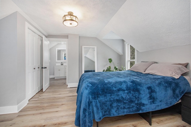 12934 Wilson Rd, Fruitport, MI 49415 - bedroom featuring light wood-type flooring, baseboards, vaulted ceiling, and a textured ceiling