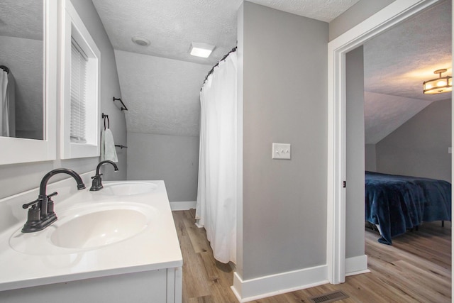 12934 Wilson Rd, Fruitport, MI 49415 - ensuite bathroom with ensuite bath, a textured ceiling, a sink, and wood finished floors