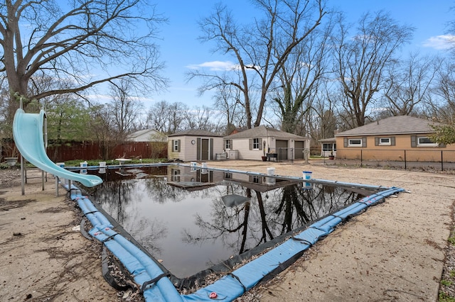 view of swimming pool with a fenced in pool, a fenced backyard, an outdoor structure, and a water slide
