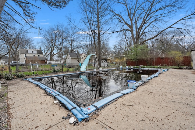 view of swimming pool with an outdoor structure, fence, and a residential view