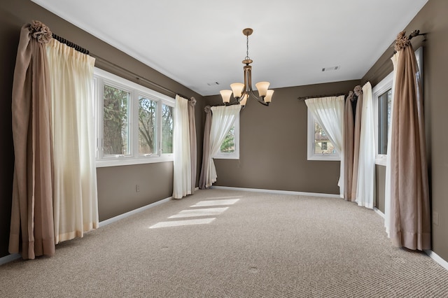 spare room with carpet floors, baseboards, and an inviting chandelier