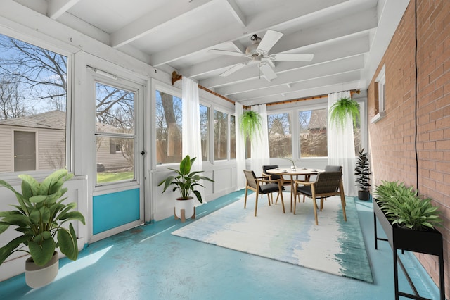 sunroom / solarium featuring brick wall, finished concrete floors, a ceiling fan, and outdoor dining space