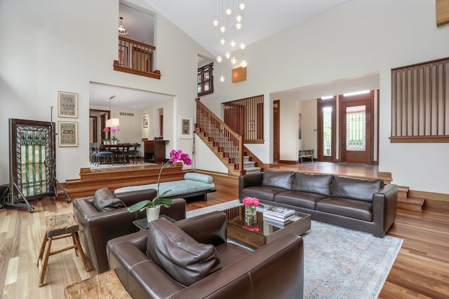 living area with a towering ceiling, wood finished floors, and stairway