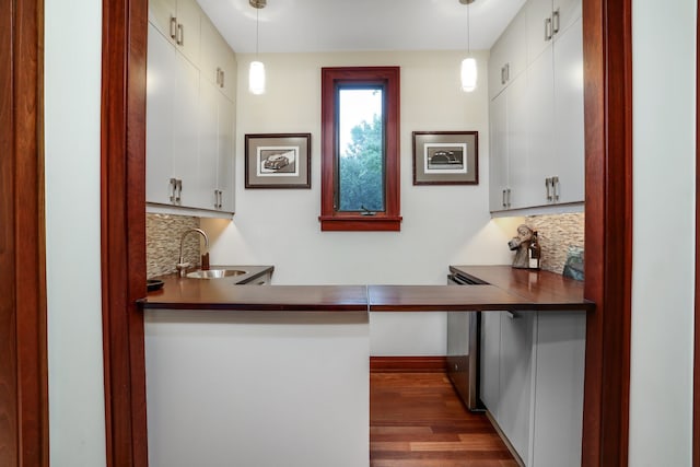 indoor wet bar featuring decorative backsplash, decorative light fixtures, and wood finished floors