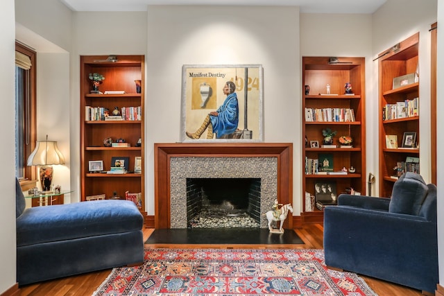 living room with wood finished floors and a tiled fireplace