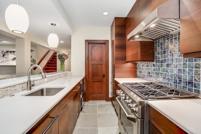 kitchen with double oven range, range hood, a sink, tasteful backsplash, and light countertops