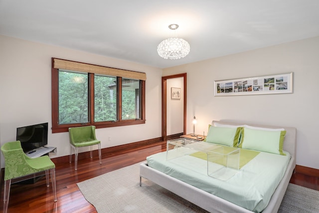 bedroom with a chandelier, wood finished floors, and baseboards
