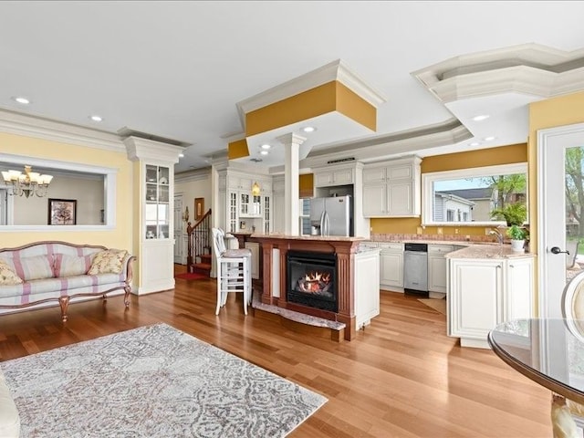 2011 W Lake Dr, Novi, MI 48377 - living room with crown molding, light wood finished floors, ornate columns, a chandelier, and stairway
