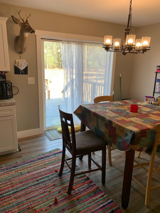 dining space featuring a chandelier, light wood-style floors, and baseboards