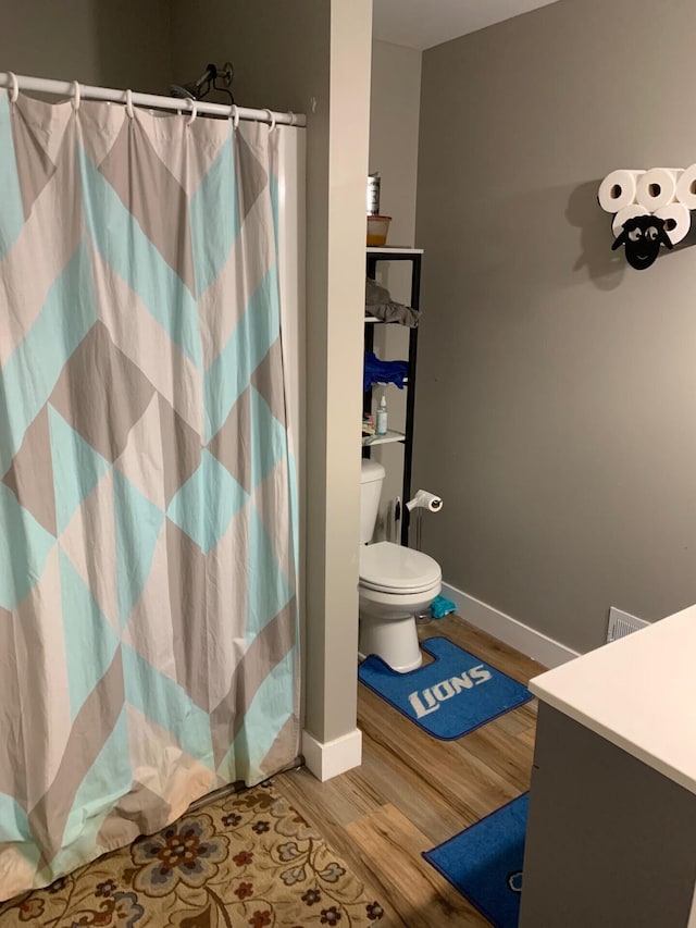 full bathroom featuring curtained shower, baseboards, toilet, and wood finished floors