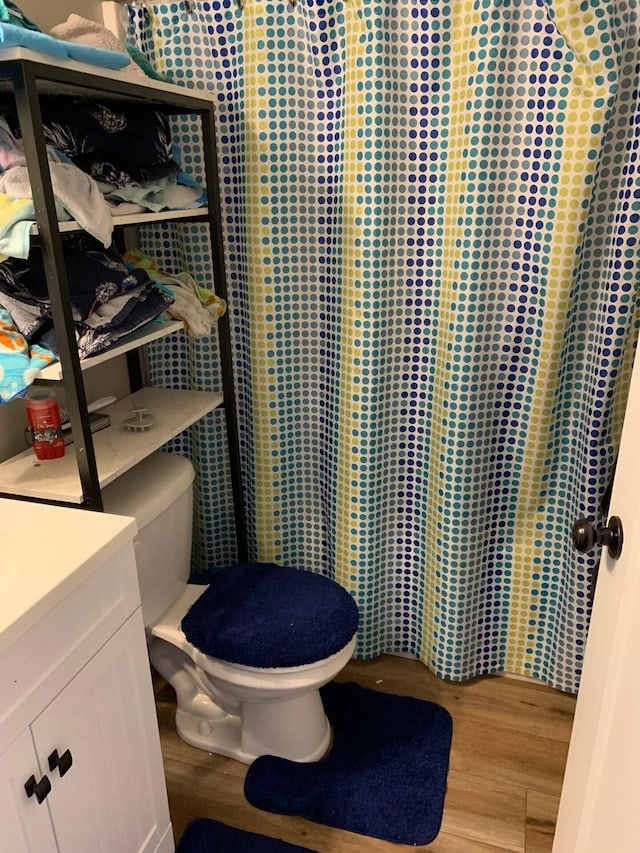 bathroom with toilet, a shower with shower curtain, vanity, and wood finished floors