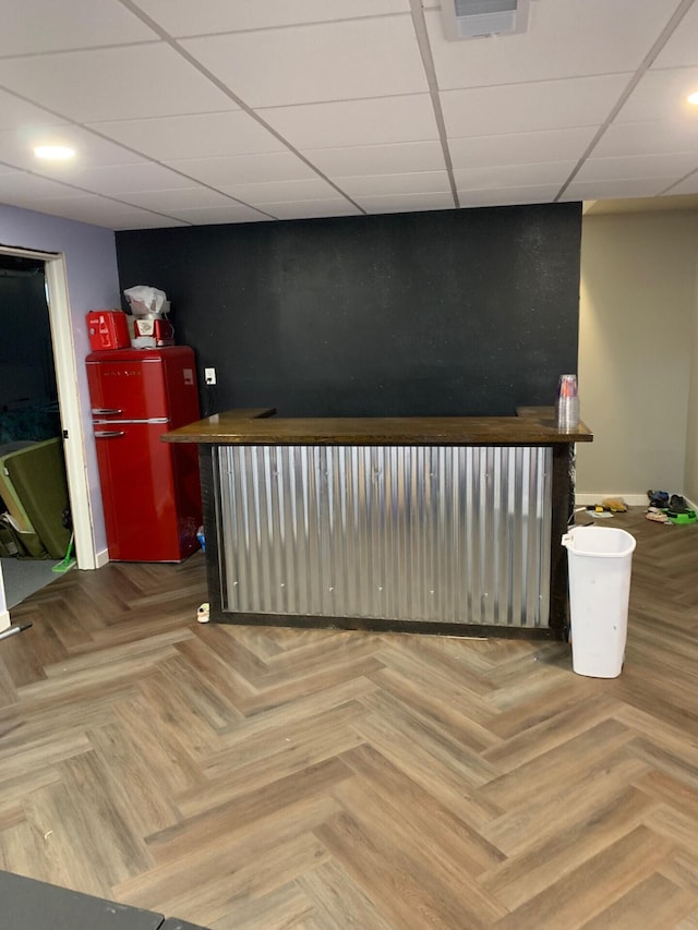 bar featuring a bar, a drop ceiling, refrigerator, and visible vents