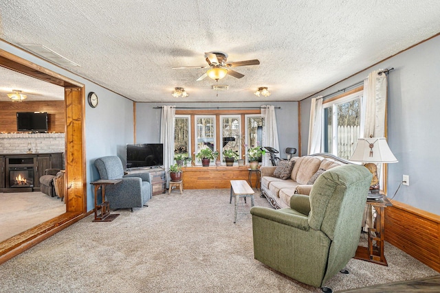 carpeted living area featuring a brick fireplace, a textured ceiling, a ceiling fan, and visible vents
