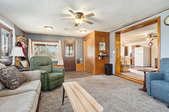 living area featuring carpet floors, ceiling fan, and a textured ceiling