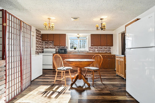 kitchen with a chandelier, dark wood-type flooring, and white appliances