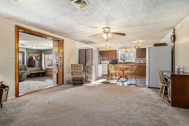 interior space with visible vents, light colored carpet, a textured ceiling, and ceiling fan with notable chandelier
