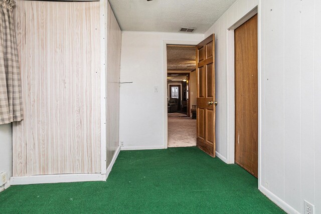carpeted spare room featuring visible vents, baseboards, and a textured ceiling