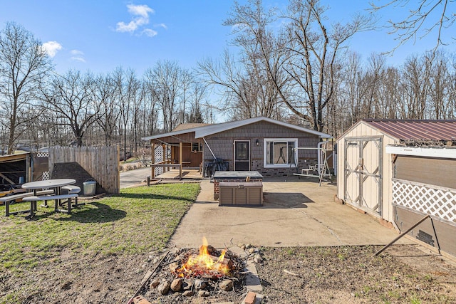 rear view of house with a patio, a fire pit, an outbuilding, a lawn, and a storage unit