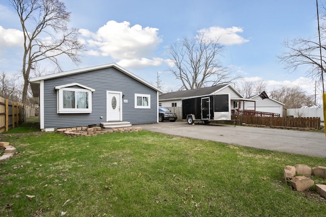 back of property with a yard, driveway, and fence