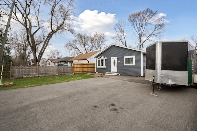 exterior space with entry steps, driveway, fence, and a lawn