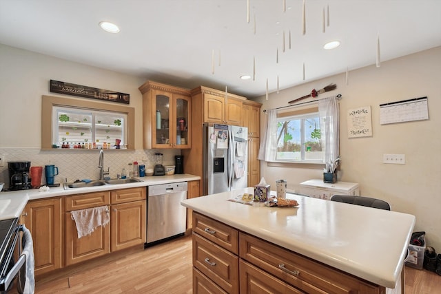 kitchen featuring light wood-style flooring, tasteful backsplash, appliances with stainless steel finishes, and a sink