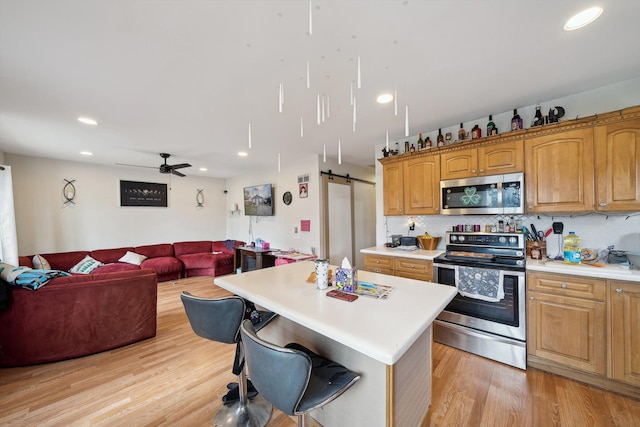 kitchen with tasteful backsplash, open floor plan, light countertops, light wood-style floors, and appliances with stainless steel finishes