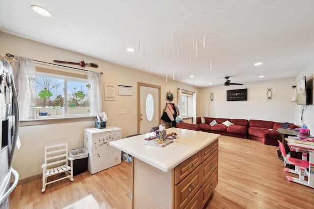 kitchen with open floor plan, light wood-style floors, light countertops, and a kitchen island