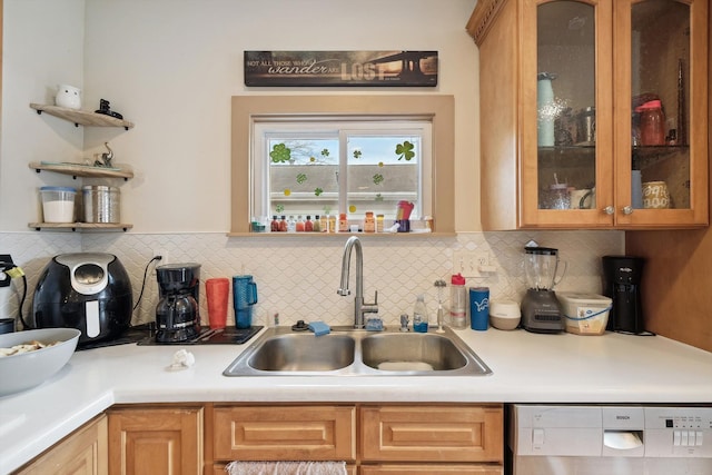 kitchen featuring glass insert cabinets, light countertops, decorative backsplash, dishwashing machine, and a sink